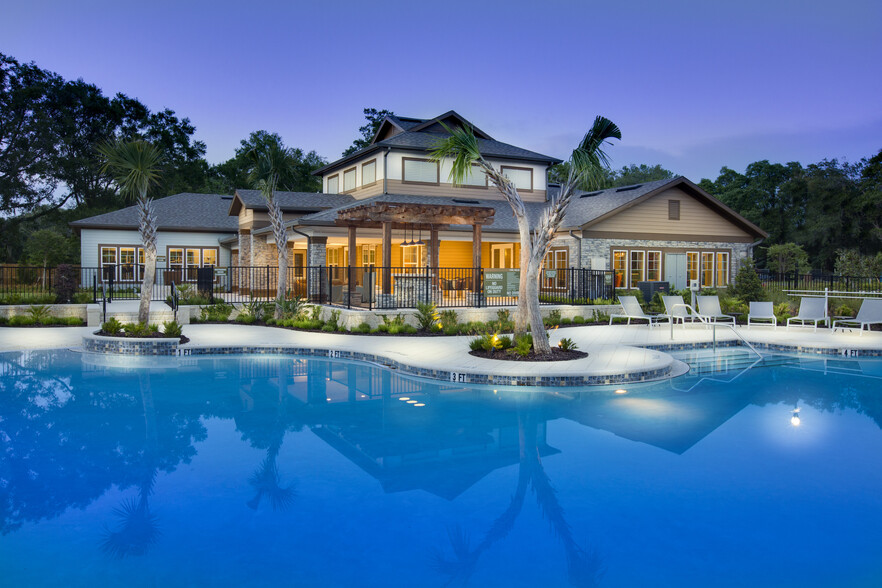 Photo overlooking swimming pool with outdoor seating, with the clubhouse in the backrgound. - Brookview at Citrus Park