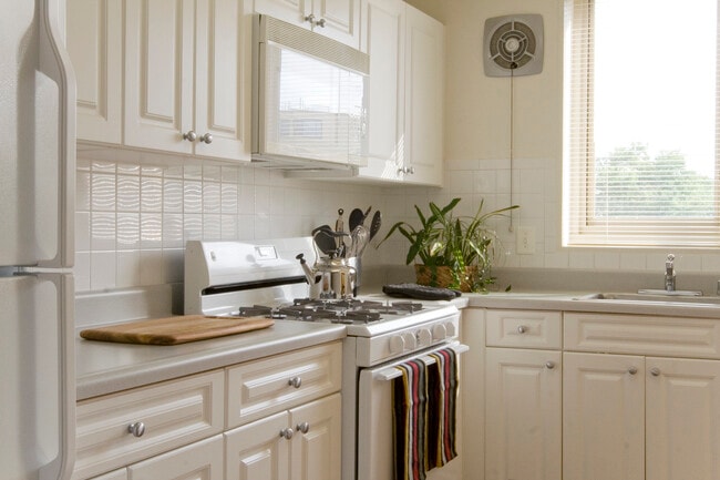 Kitchen with white cabinetry, white countertops, white appliances and tile backsplash - Avalon The Albemarle