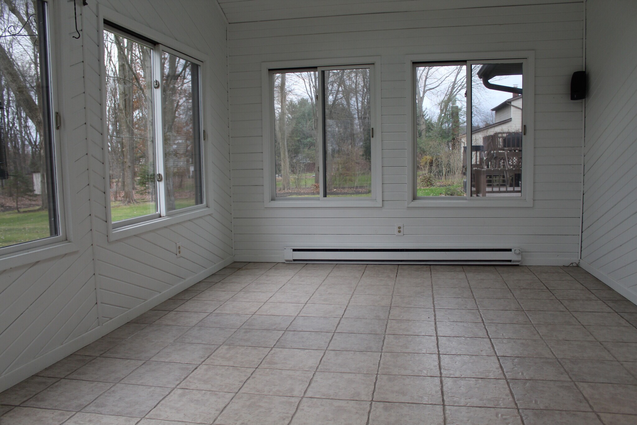Bright tiled sunroom with large windows on three sides overlooking the backyard. - 6235 Sunnywood Dr