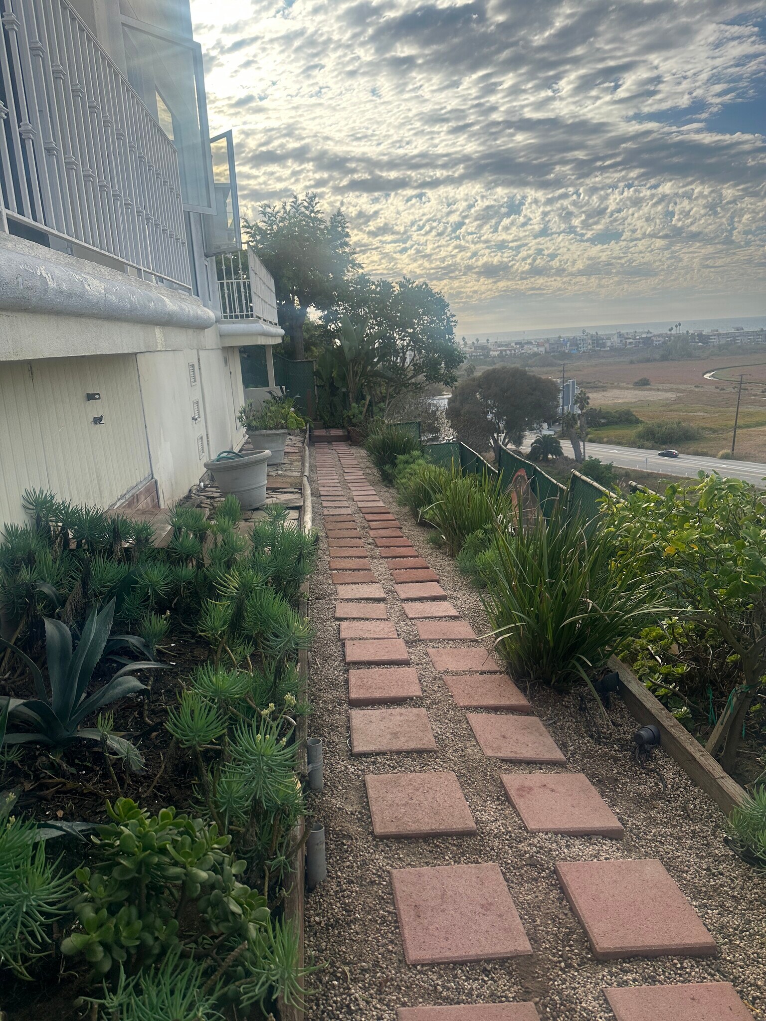 Tranquil garden walkways invite quiet reflection, framed by lush greenery and coastal breezes. - 8120 Billowvista Dr