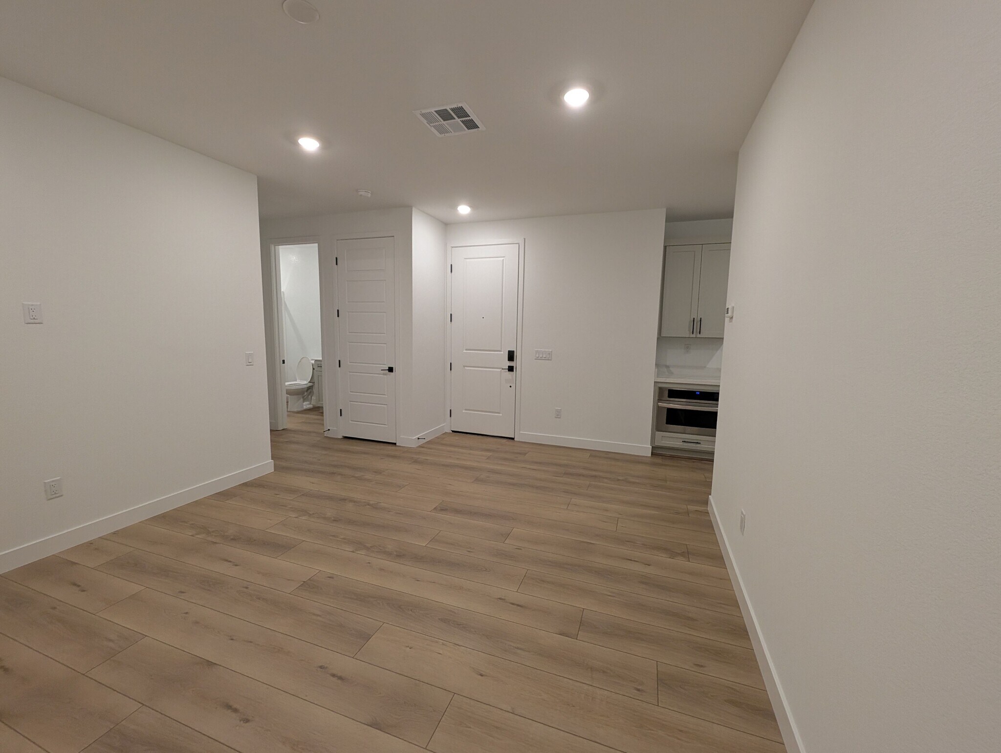 Large 18' x 13' living room with modern plank flooring and large window - 628 S Cecita Wy