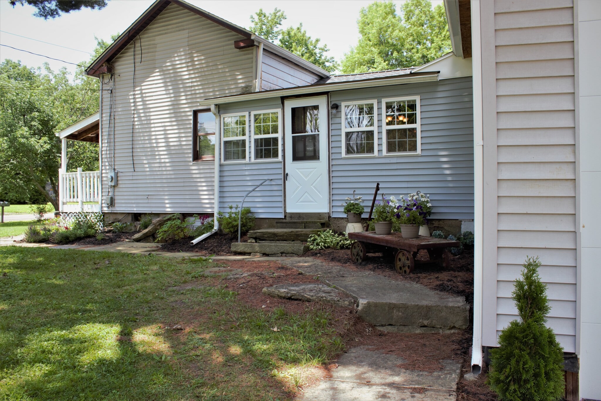 Private entrance from east side (driveway side) of home. All newer windows, newer storm door, newer gutters. Decorative historic railroad cart holds flowers. Sidewalk leads from garage to east and south entrances. - 9331C Tallmadge Road