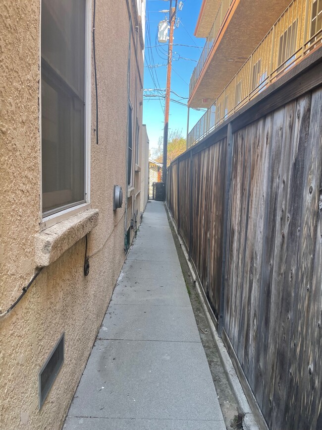 Triplex walkway to trashcans in alley beyond locked gate. - 1749 E 3rd St