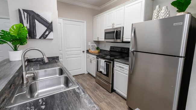 Cook, clean, and entertain with ease in this fully equipped kitchen,featuring stainless-steel appliances, white shaker cabinets, and wood-style flooring. - Elevate 155