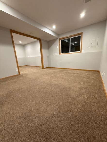 Spacious lower bedroom with neutral carpet and recessed lighting. - 9092 Goldenrod Ln N