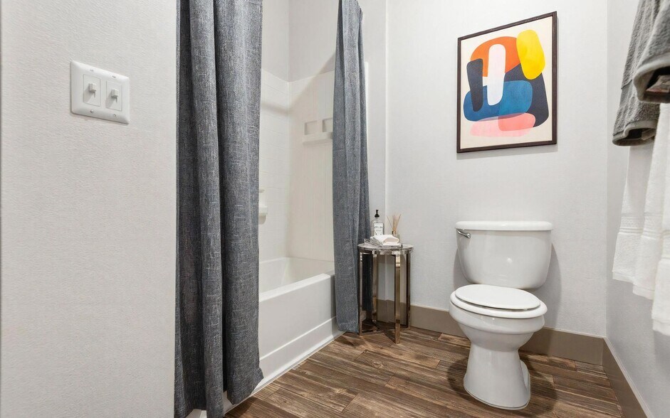 Compact Bathroom Featuring Toilet, Tub, and Small Accent Table - REVERB