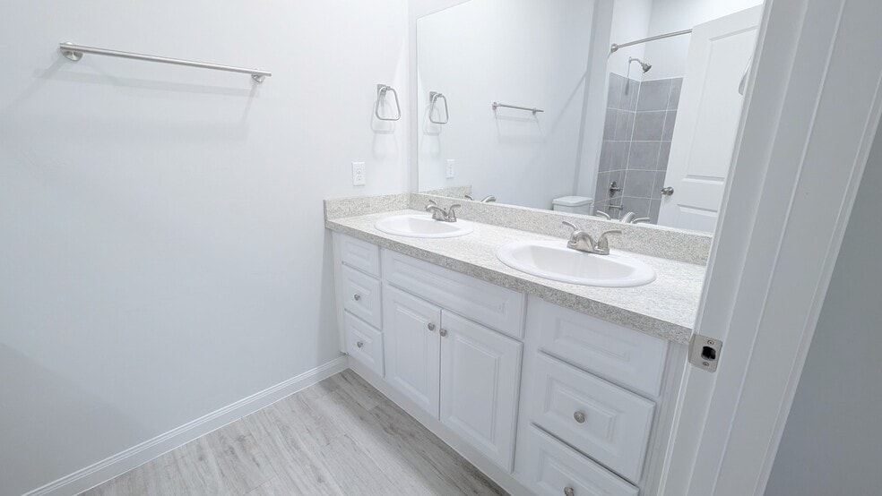 Primary bath features dual vanities, a large mirror, and plenty of cabinet storage space. - 13218 HP Johnson St