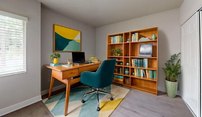Bright and inviting home office with a wooden desk, teal chair, and stylish bookcase, featuring lush greenery and vibrant artwork. - Soto Apartments