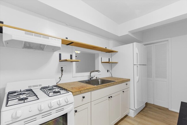 Second kitchen on the first floor with white cabinets and has a pass-through window. - 45 High St