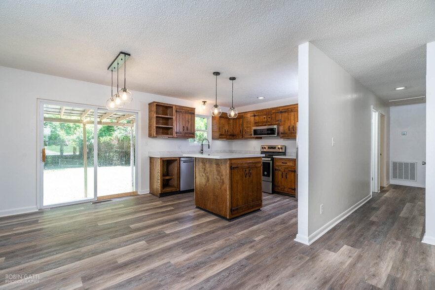 Kitchen equipped with new lighting fixtures, island, countertops, flooring, and stainless steel appliances - 502 Cherokee Court
