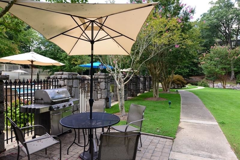 Tables and Chairs with umbrellas at pool - 25116 Plantation Dr NE