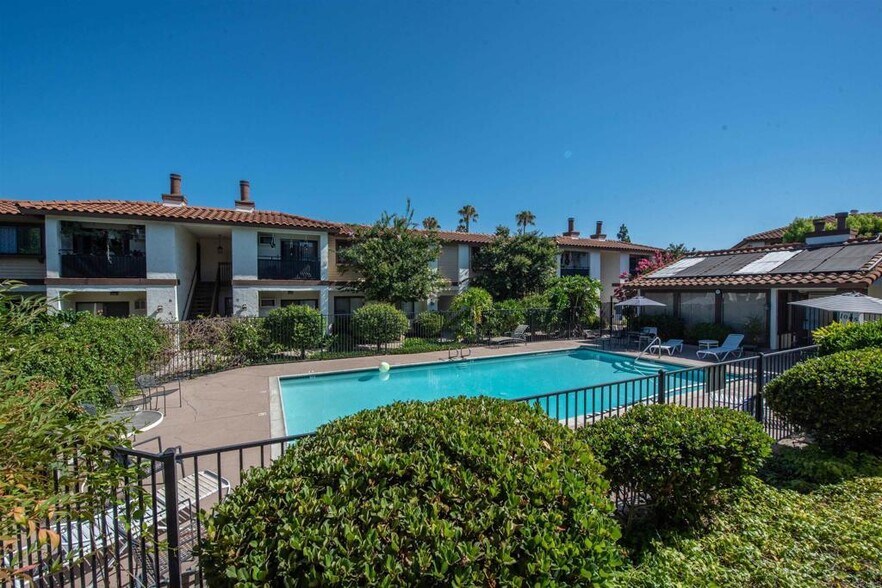 Resort-style pool surrounded by lush landscaping and lounge seating. - 1013 S Sunshine Ave