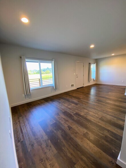 Spacious living area featuring large windows, dark wood-style flooring, and recessed lighting. - 575 Greenwood Ave