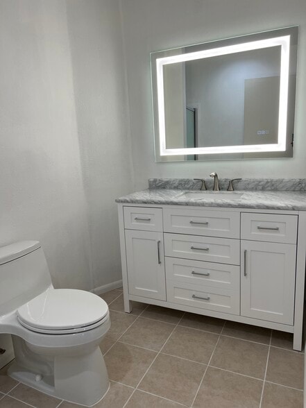 Master bath vanity with marble countertop and lighted mirror. - 5710 Baltimore Dr