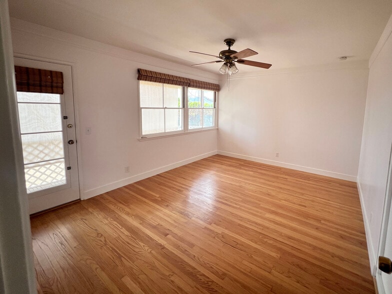 Bedroom with ceiling fan, door to back balcony on the left. - 1327 N Central Ave