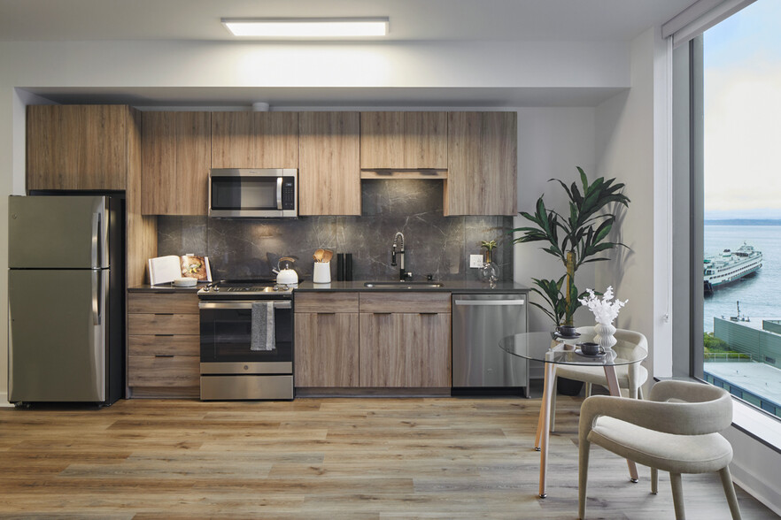 Apartment kitchen with stainless steel appliances, quartz countertops and wood-style flooring. - Griffis Seattle Waterfront