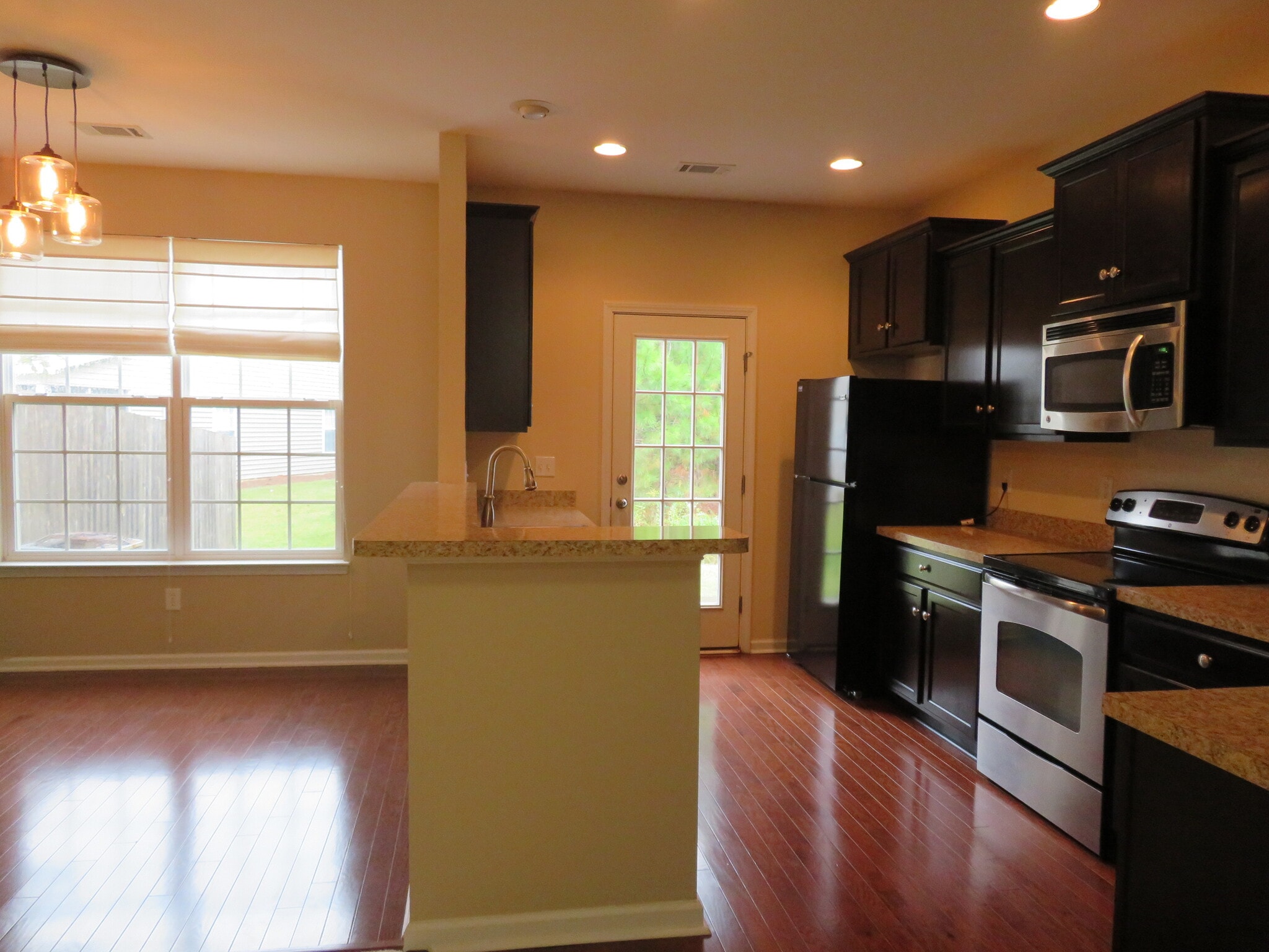 Dining left, Eat-In bar, Kitchen. View to backyard through French door. *Note - Upgraded lighting - 2496 Stadium Dr