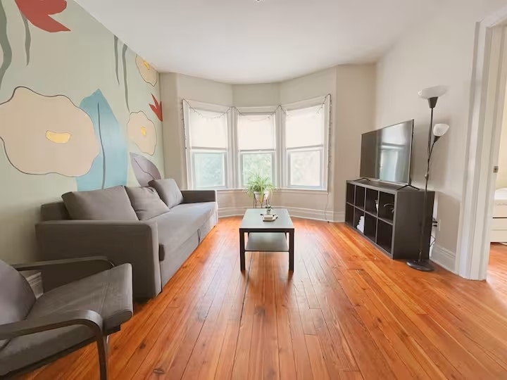 Enjoy our living room with a pull-out sofa, a 55-inch UHD Roku TV & custom mural hand-painted. - 203 W Tupper St