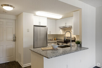 Renovated Package III kitchen with white cabinetry, grey granite countertops, stainless steel appliances, and hard surface flooring - eaves Washingtonian Center