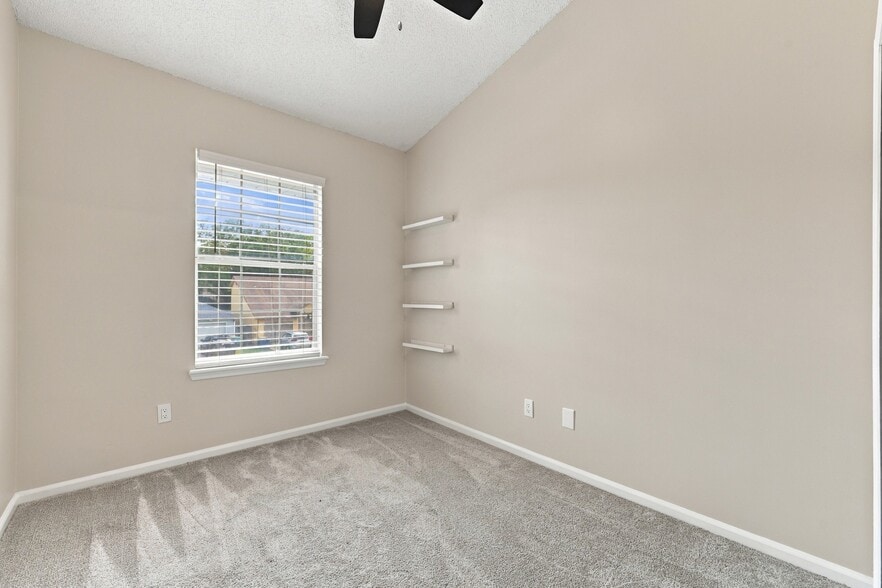 Secondary bedroom with brand-new carpet and built-in wall shelving. - 3622 Caroline Vale Blvd