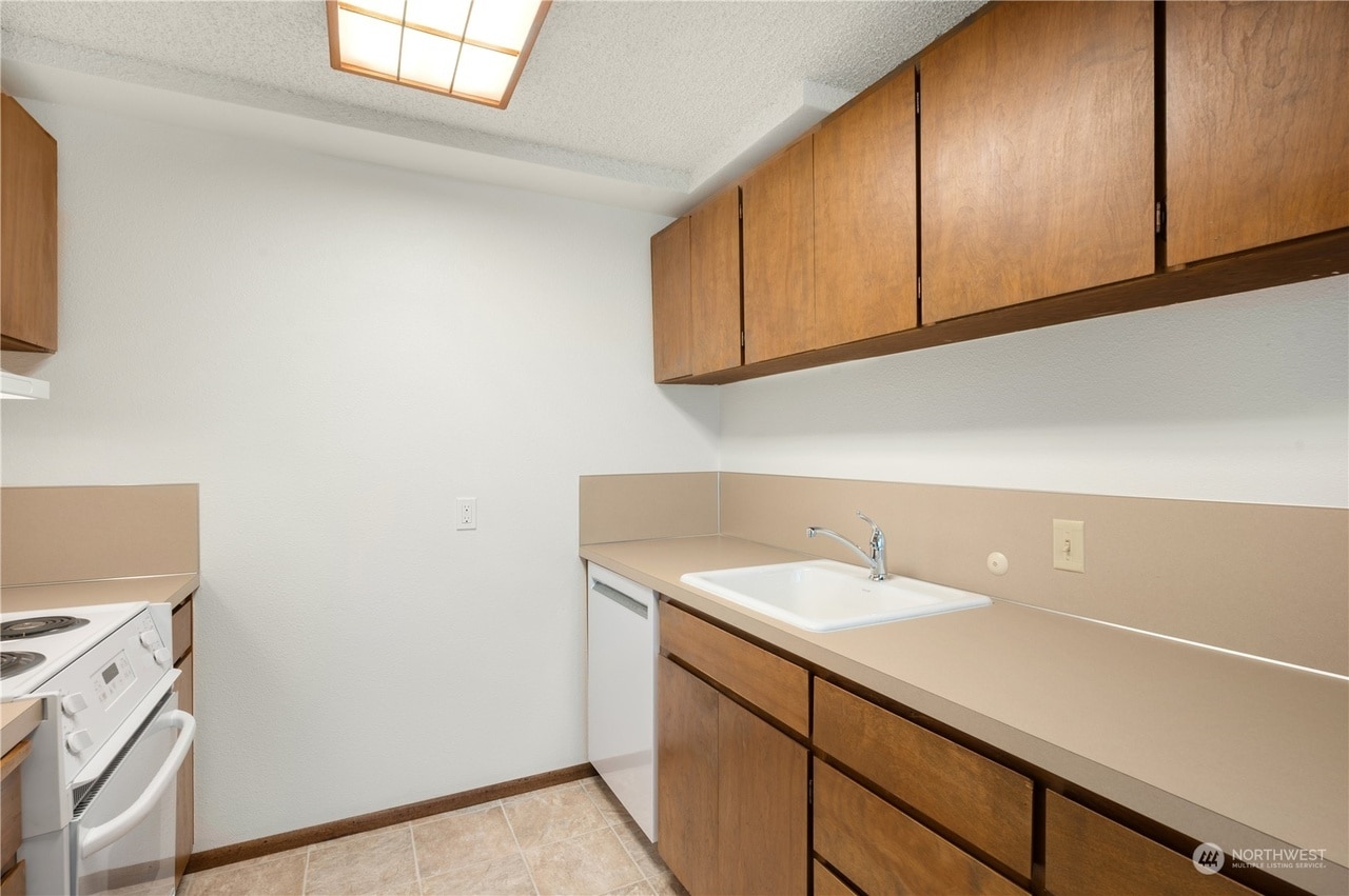 The galley kitchen features new appliances, including oven+stove, dishwasher, and fridge. - 3033 21st Ave W