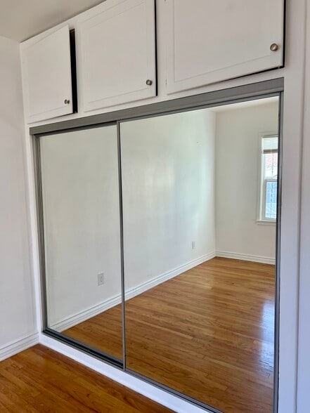 Comfortable bedroom with mirrored closet doors, generous storage space, windows, and remote-control - 3551 W Manchester Blvd