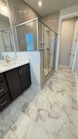 Spa-inspired primary bath with dual vanities and glass-enclosed shower. - 4720 Cypress Tree Ln