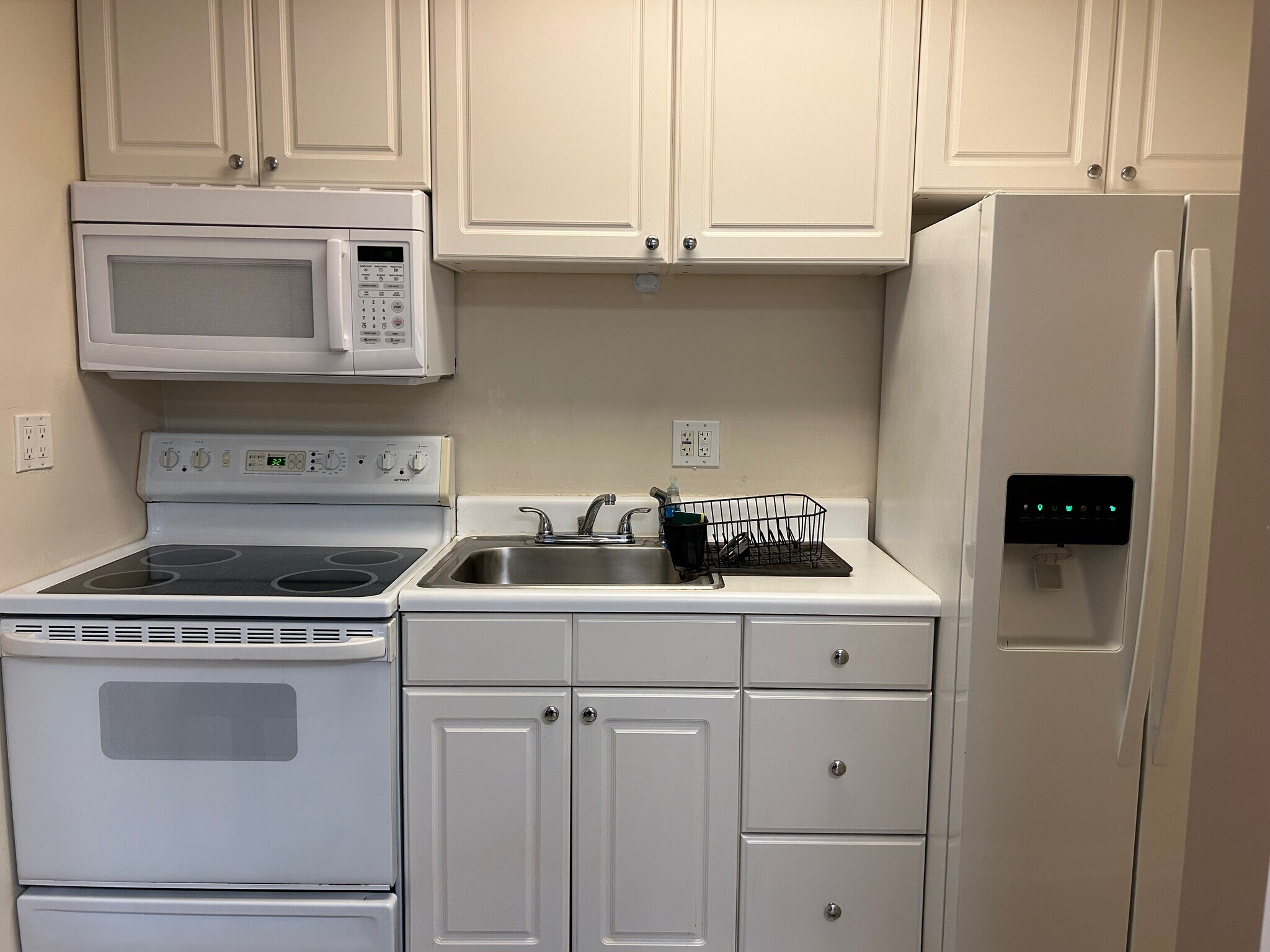 white kitchen w/full size refrigerator/stove/microwave - 630 NW 7th Ave