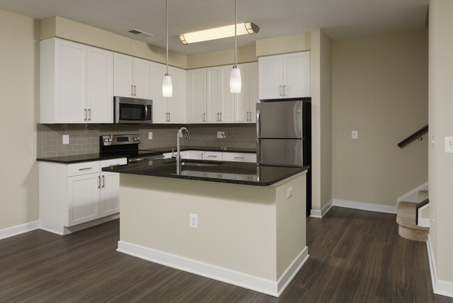 Townhome open concept kitchen with granite countertops and white shaker cabinetry, kitchen island, stainless steel appliances and hard surface flooring - Avalon Laurel