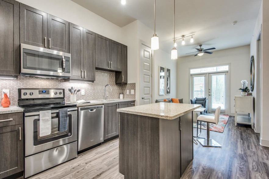 Inwood Stations offers chef-caliber kitchens with elegant cabinetry and tile backsplash. This color scheme is Smoky with a grey tile backsplash. - Inwood Station Apartments