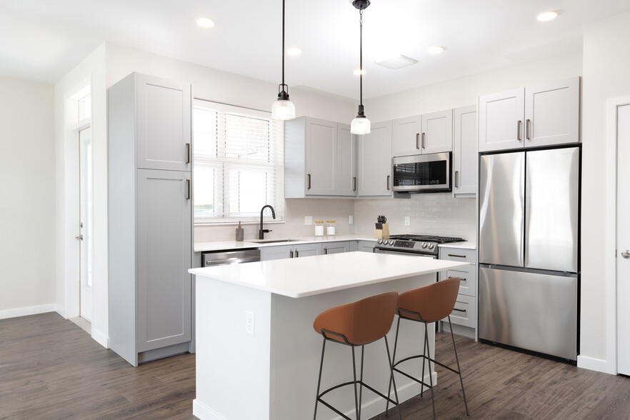 Modern kitchen with stainless steel appliances, white quartz countertop, light grey cabinetry, white tile backsplash, and hard surface flooring - Avalon Amityville