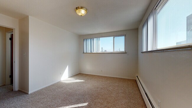 Experience comfort in this bright, minimalist room with ample natural light. - Melody Apartments