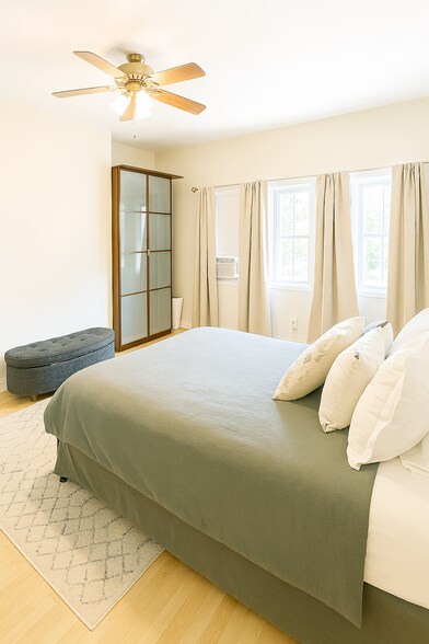 Main bedroom with a ceiling fan, two wardrobes, high ceilings, and a full wall of picture windows - 56 Jefferson Ave