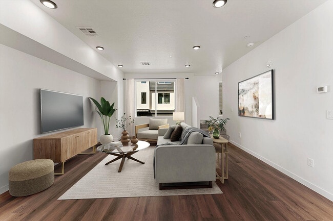 Elegant living room with modern decor, large windows for natural light, cozy seating, and stylish wooden flooring. - Coal Creek Townhomes