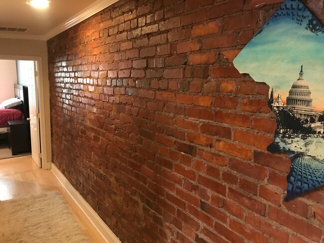 Exposed brick and hardwood continue through the hallway - 712 13th Street Northeast