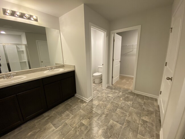 Master bath view of double sinks, toilet room and walk-in closet - 9010 Fenton Rd.