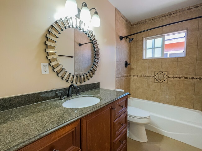 Bathroom with beautiful granite countertop and bathtub with delicate tile finish. - 12063 Lamanda St