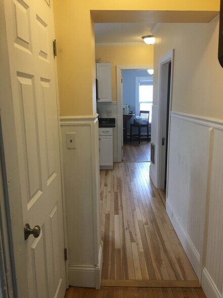 Looking down hallway from living room through kitchen to back bedroom. Door on left is side stairway to lower 3-season porch. - 1320 Jefferson St NE