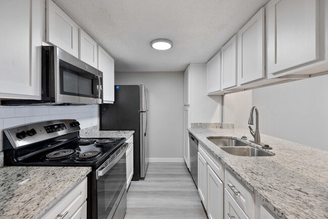 A kitchen with granite countertops and stainless steel appliances. - Fairway Greens Apartments