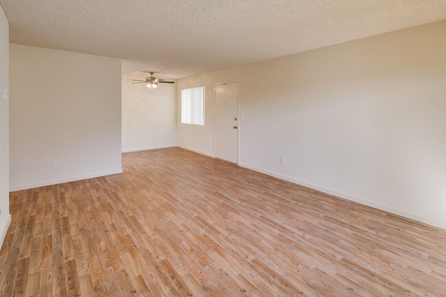 Image of living area with wood-style plank flooring and a view of the dining area with ceiling fan. - Casa De La Mesa