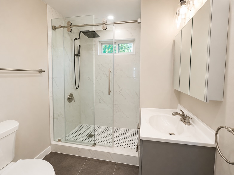 Fully renovated bathroom featuring marble-look shower tile, glass shower door, updated vanity - 78 Orchard St