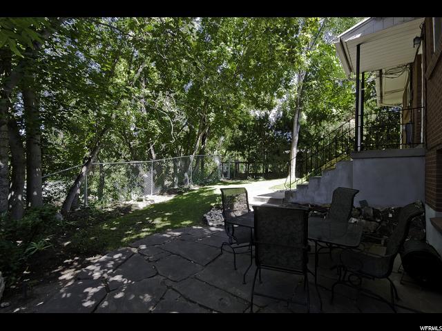 Green backyard with stone patio that backs onto Allen Park - 1319 Westminster Ave S