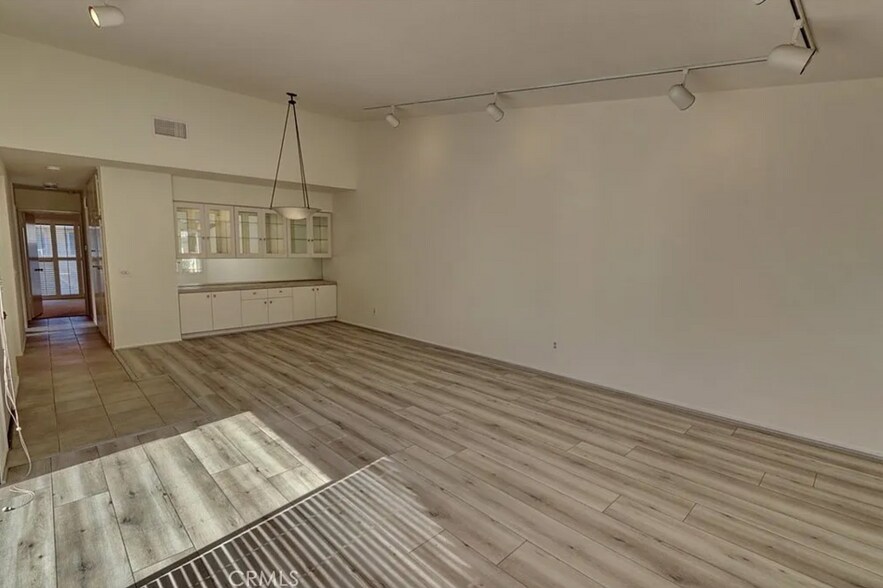 Living room & dining room with built in buffet & upper, glass front cabinets. Track lights removed. - 8566 Larkhall Cir