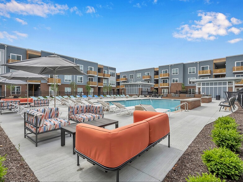 An aerial view of our heated pool with lounge seating, tables, a grilling station, and a community fireplace - Graceland Flats