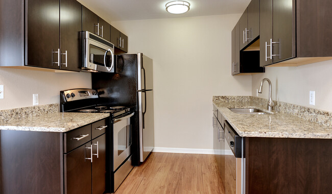 Kitchens offer stainless steel appliances and wood flooring - Boulder Creek Apartments