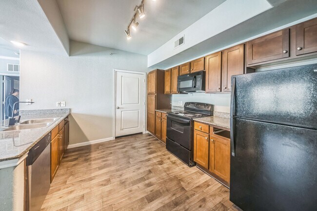 Kitchen with black appliances and brown cabinets - Summit at Hirsch Road