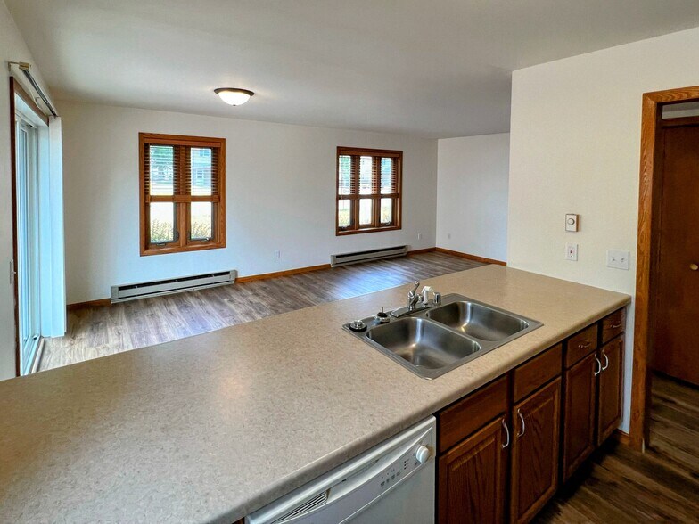 bright kitchen with ample countertop space, wood cabinetry, and dishwasher overlooking living area - 213 Ash Street