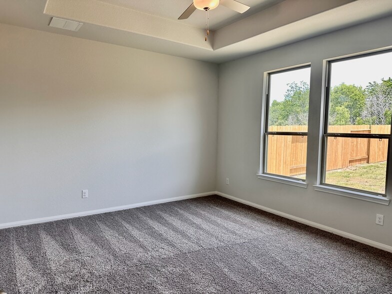 The spacious primary suite offers a ceiling fan and carpet! - 730 Tejas Village Pky