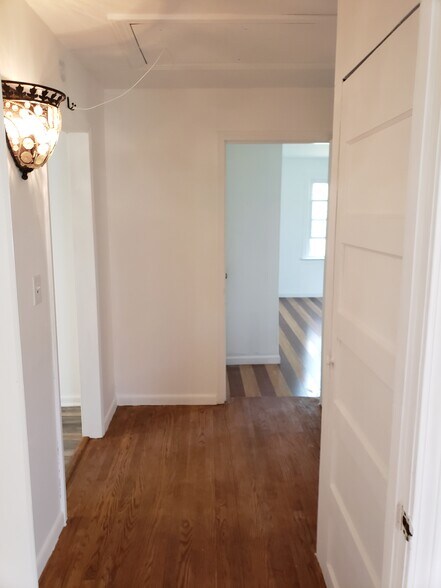Hallway has refinished original hardwood flooring, coat closet with vintage 5 panel door and pull down ladder for attic storage access. - 10106 Wingfield Rd