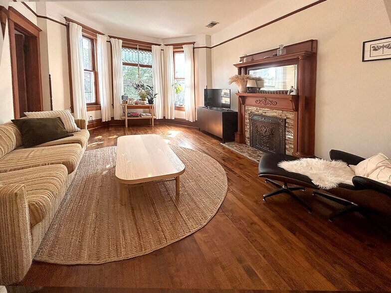 living room has bay window with leaded glass, decorative mantle and high ceilings - 952 N Hoyne Ave